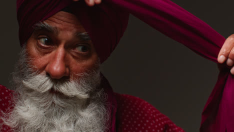 Low-Key-Studio-Lighting-Shot-Of-Senior-Sikh-Man-With-Beard-Tying-Fabric-For-Turban-Against-Dark-Background-2